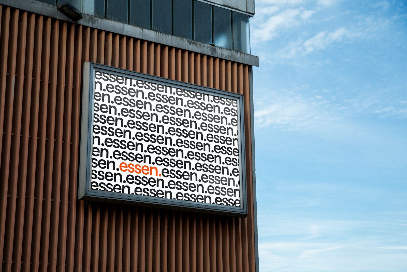 Sign with repeating word "essen" against blue sky